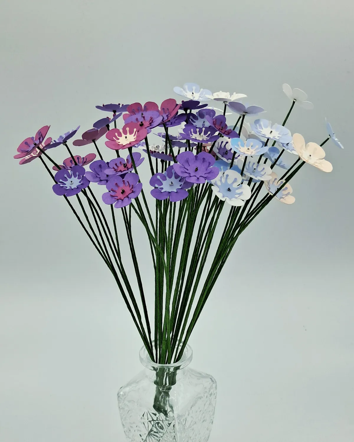 Bouquet de fleurs de wax bleues et violettes dans un vase en verre